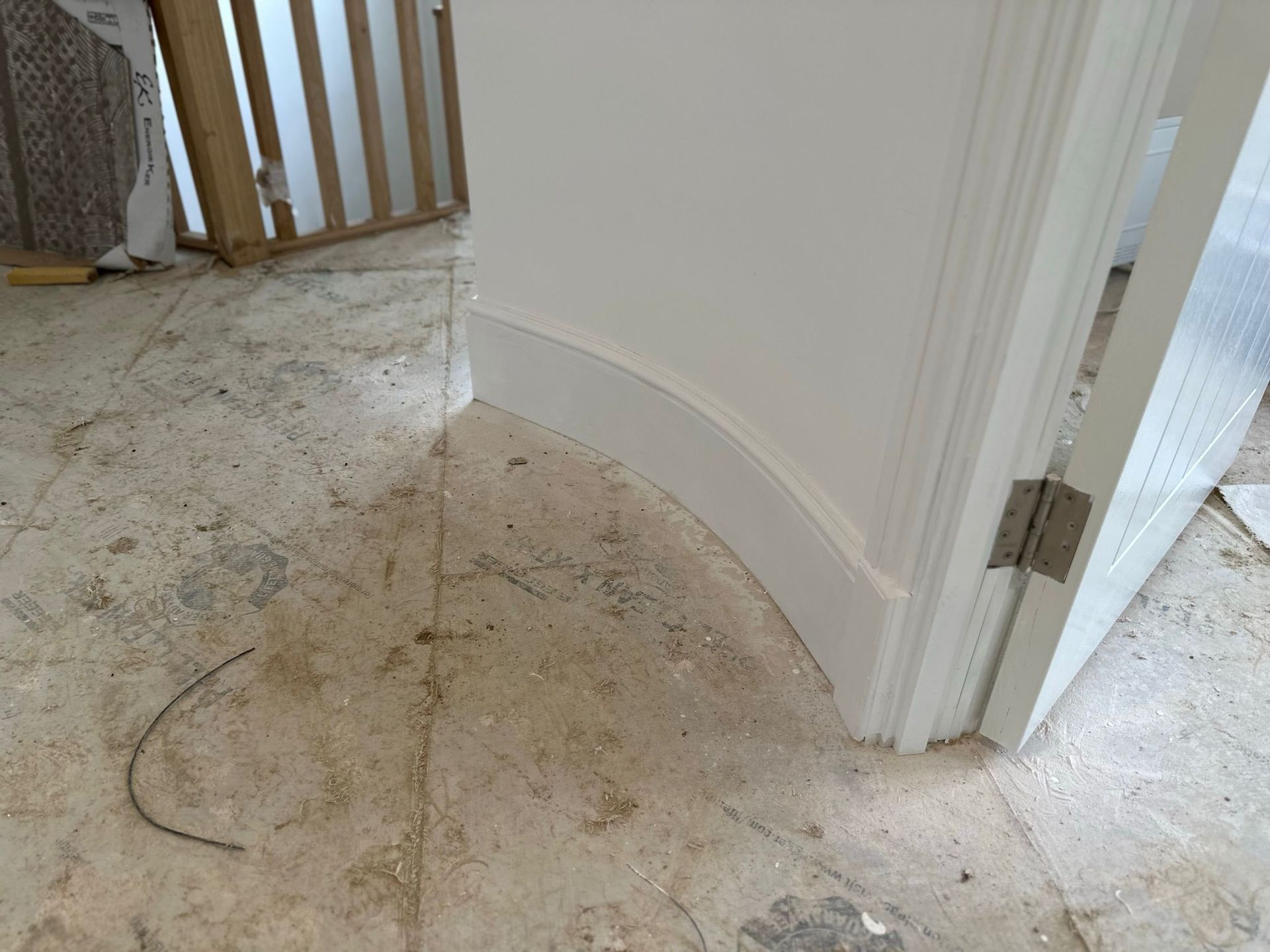 Curved white trim at doorway corner, unfinished flooring.