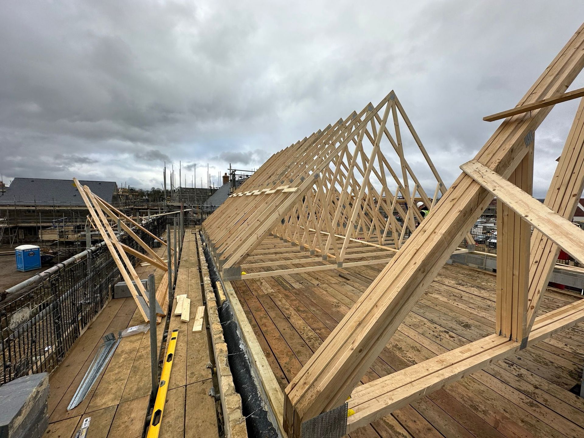 Construction of a wooden roof frame on a building, under a cloudy sky.
