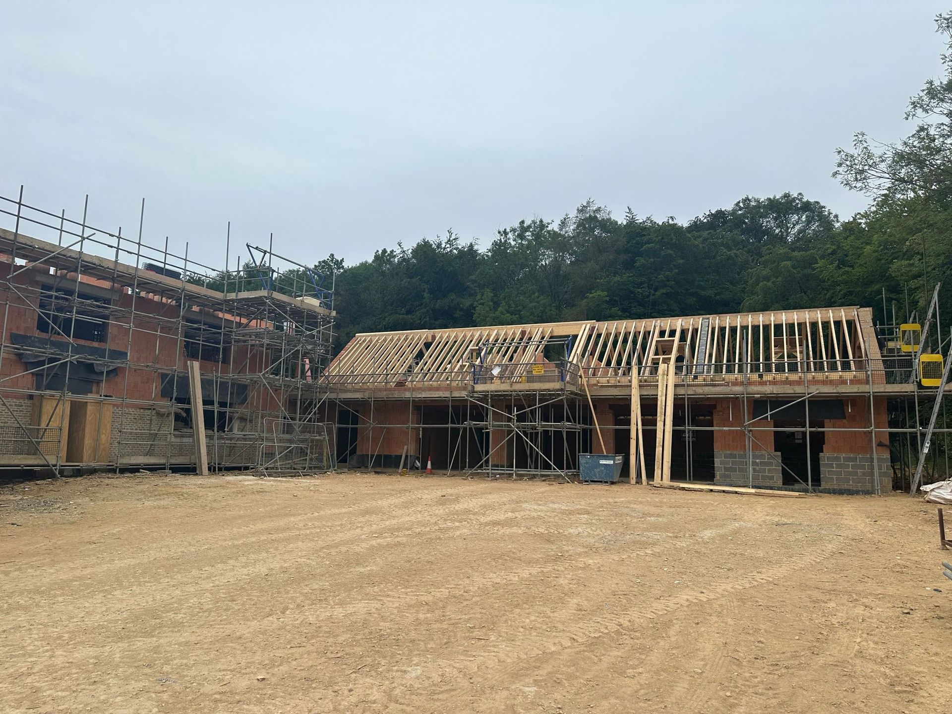 Construction site with brick structures, wooden framing, and scaffolding, under cloudy skies.