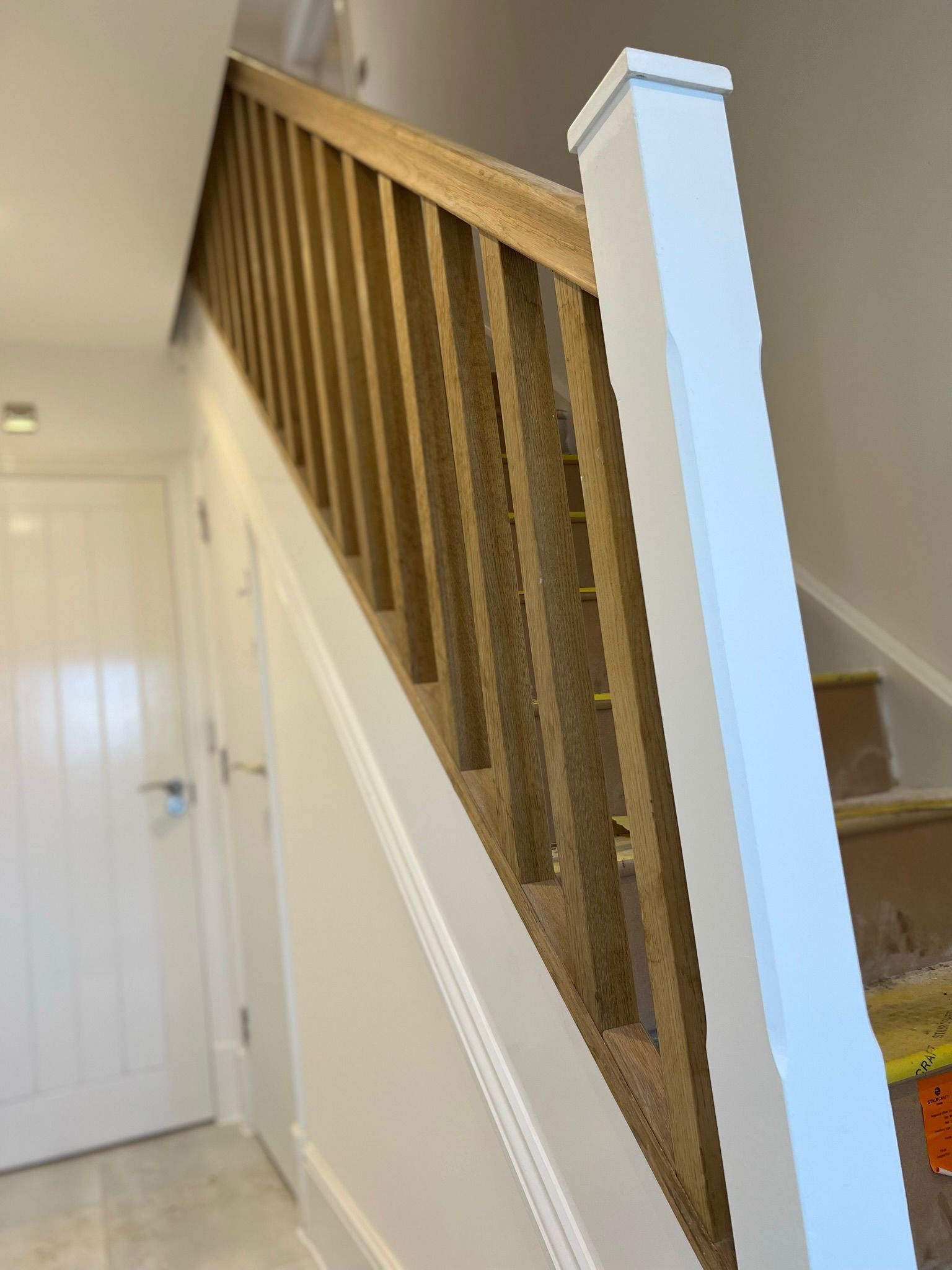 Wooden staircase with light brown balustrade and white trim.