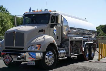 A tanker truck is being filled with gas at a gas station.