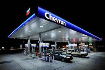 A chevron gas station at night with cars parked in front of it.