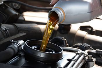 A person is pouring oil into a car engine.