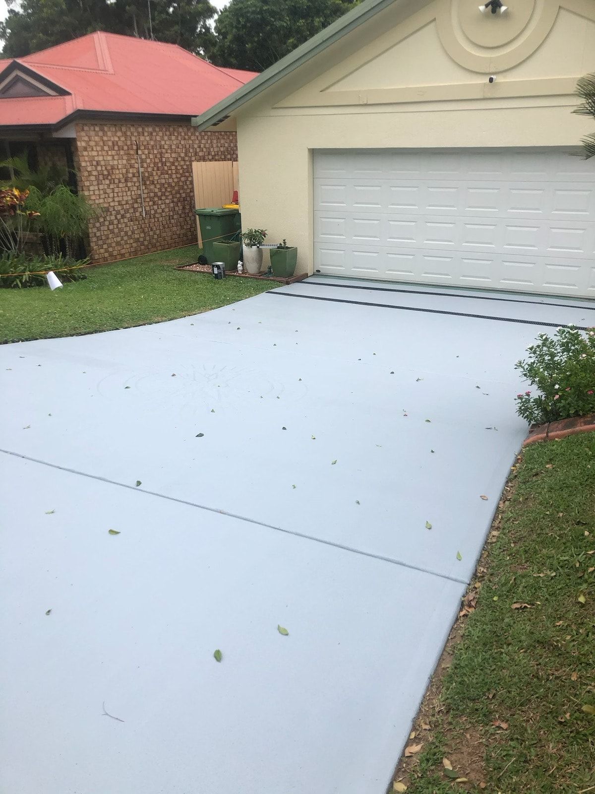 Gray Painted Driveway in Front of a House, With a Closed Garage Door — Pete's Painting Solutions In Cairns, QLD