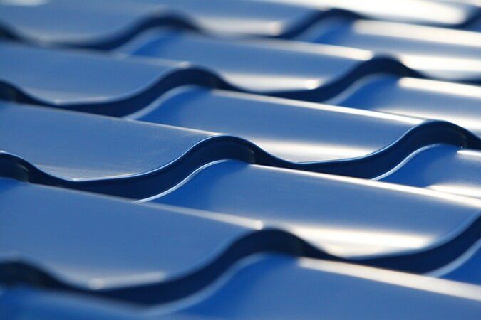 A Person Is Painting A Roof With Blue Paint — Pete's Painting Solutions In Cairns, QLD
