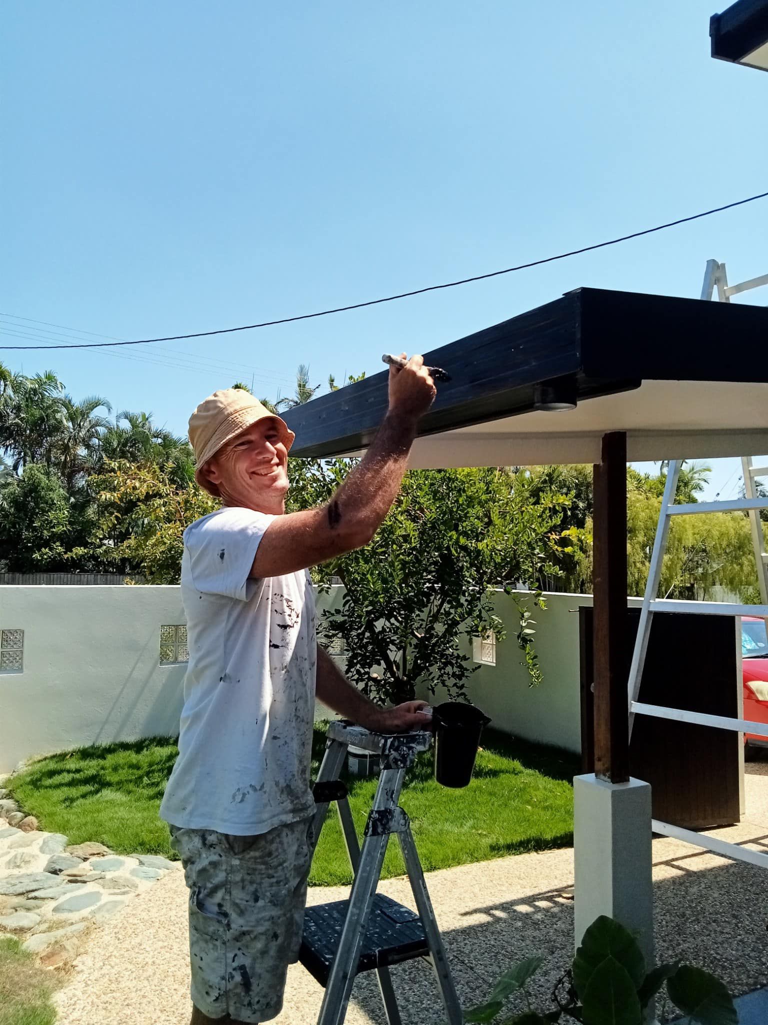 A Person Is Painting A Roof With Blue Paint — Pete's Painting Solutions In Cairns, QLD
