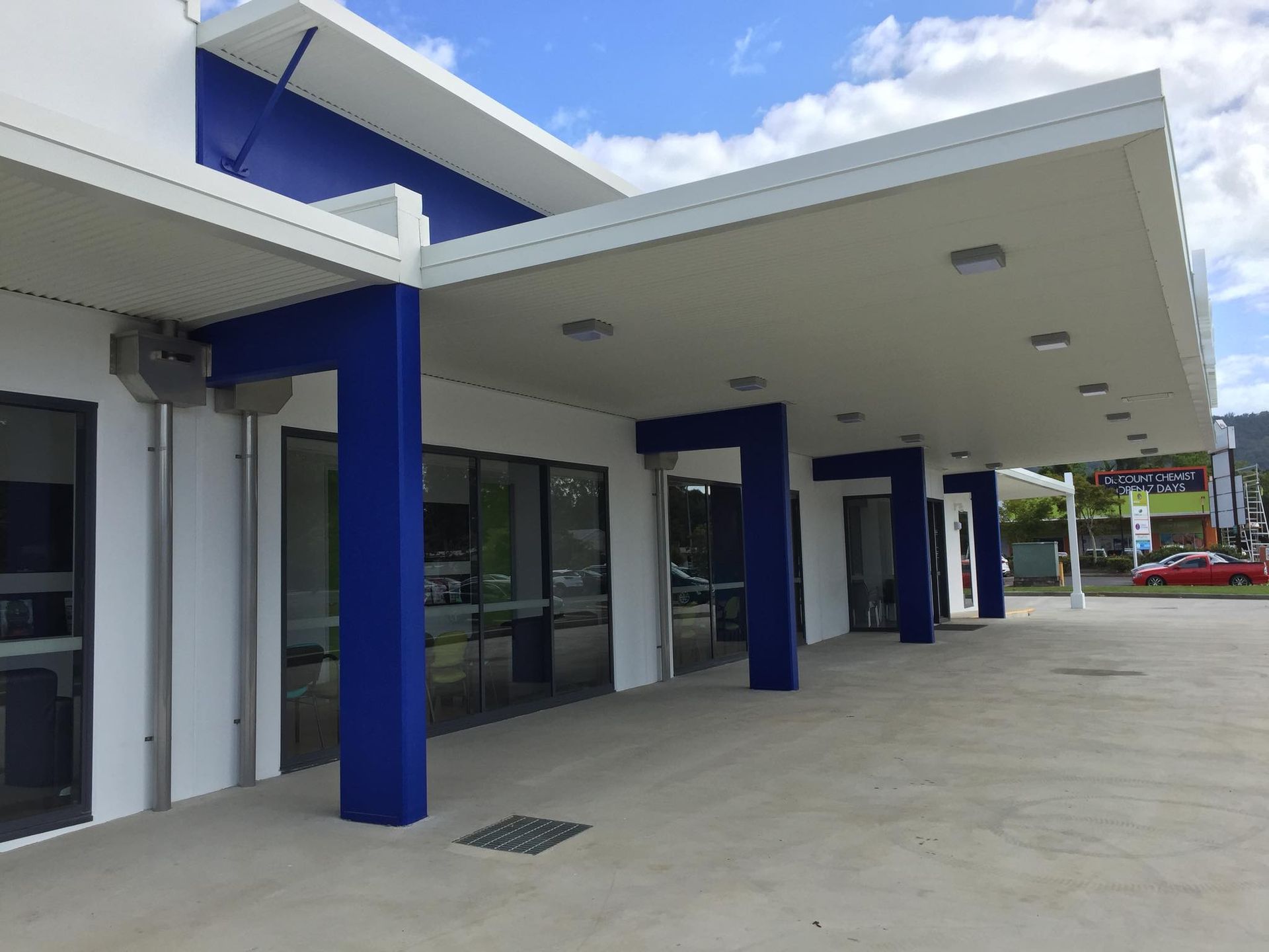 A Man Is Painting The Side Of A Building With A Paint Roller — Pete's Painting Solutions In Bentley Park, QLD