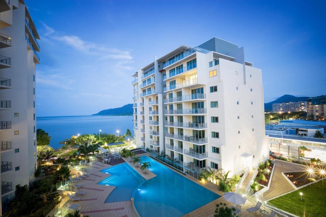 A Lit-up Resort With Pools and Ocean View at Dusk. Modern White Buildings — Pete's Painting Solutions In Cairns, QLD