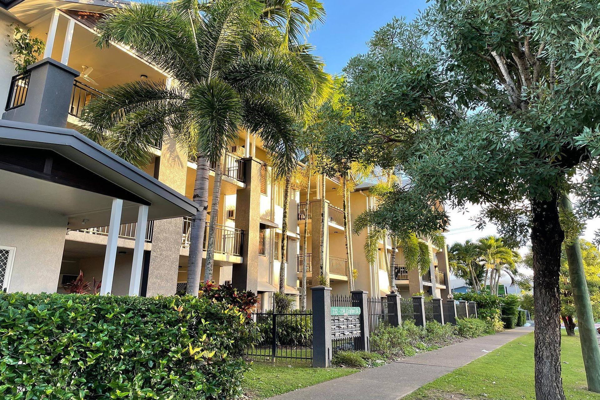 Apartment Building With Balconies and Palm Trees, Beside a Sidewalk and Green Hedge — Pete's Painting Solutions In Cairns, QLD