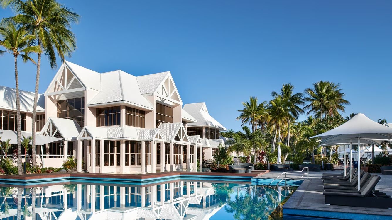 A Resort With a Pool, Palm Trees, and a White-roofed Building — Pete's Painting Solutions In Cairns, QLD