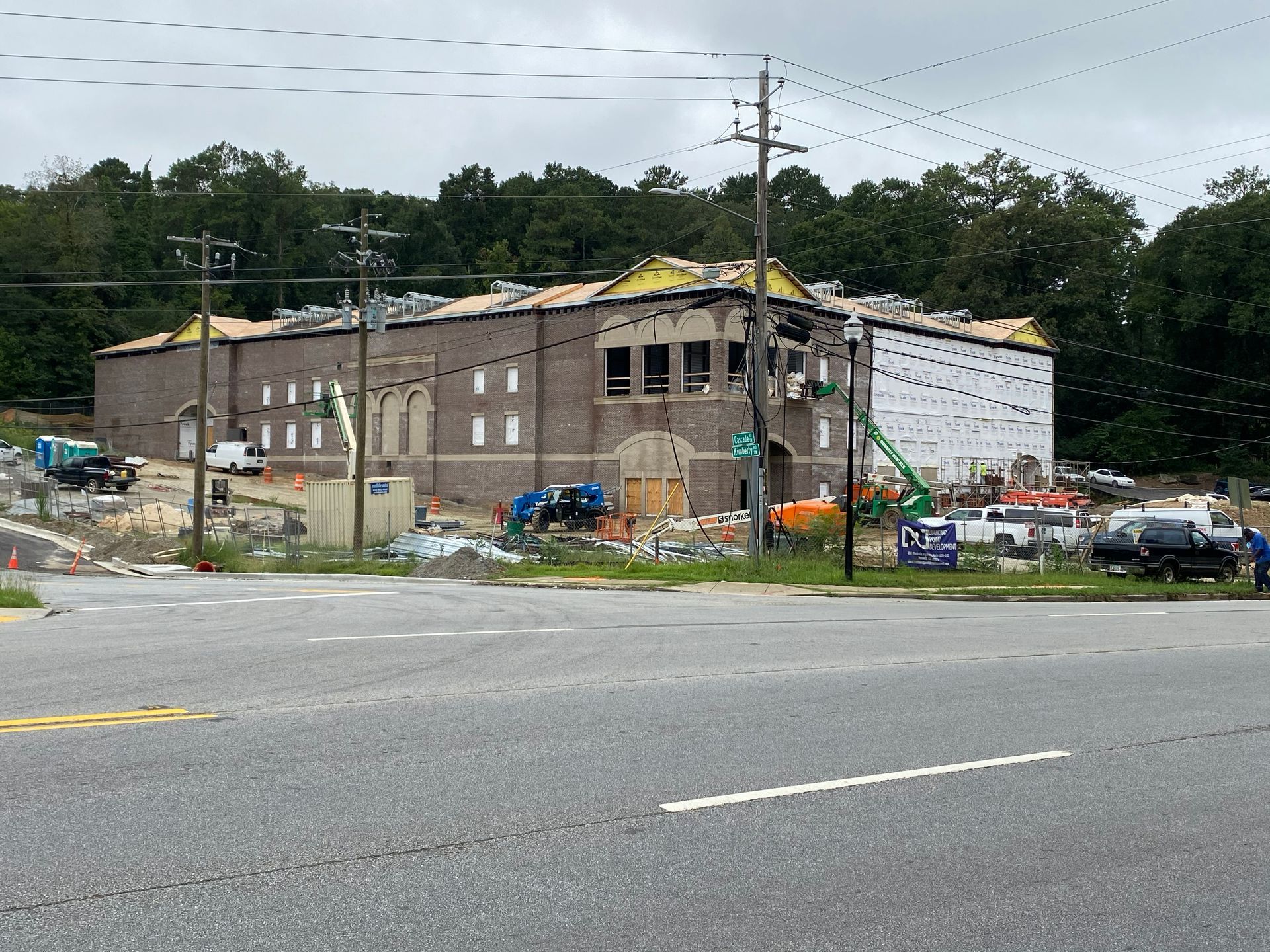 Building under construction with scaffolding, debris, and equipment; overcast sky.