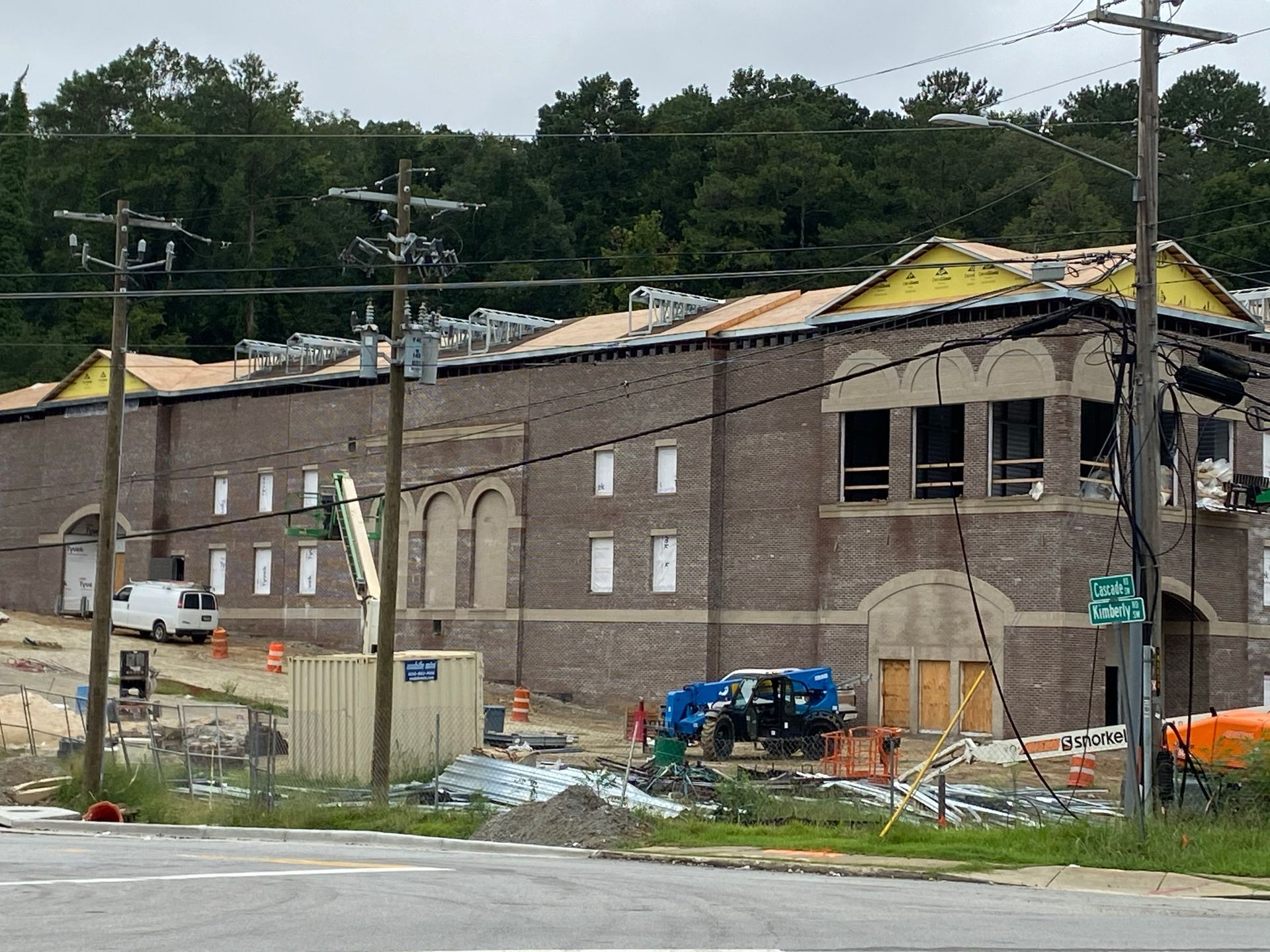 Brick building under construction with exposed roof and construction equipment.