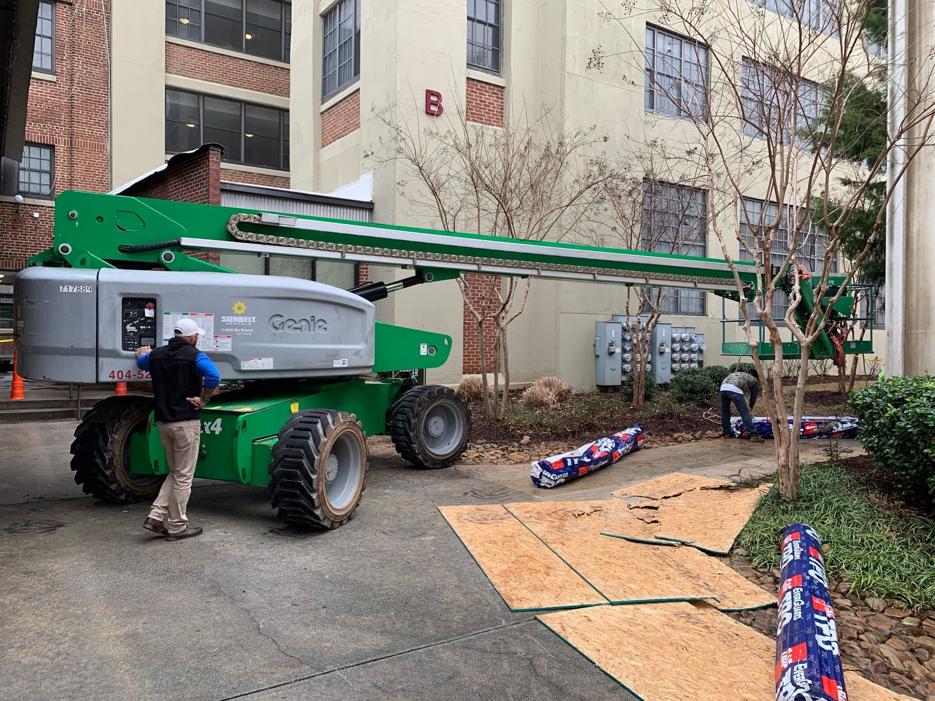 Workers beside a large lift near a building, preparing for work.
