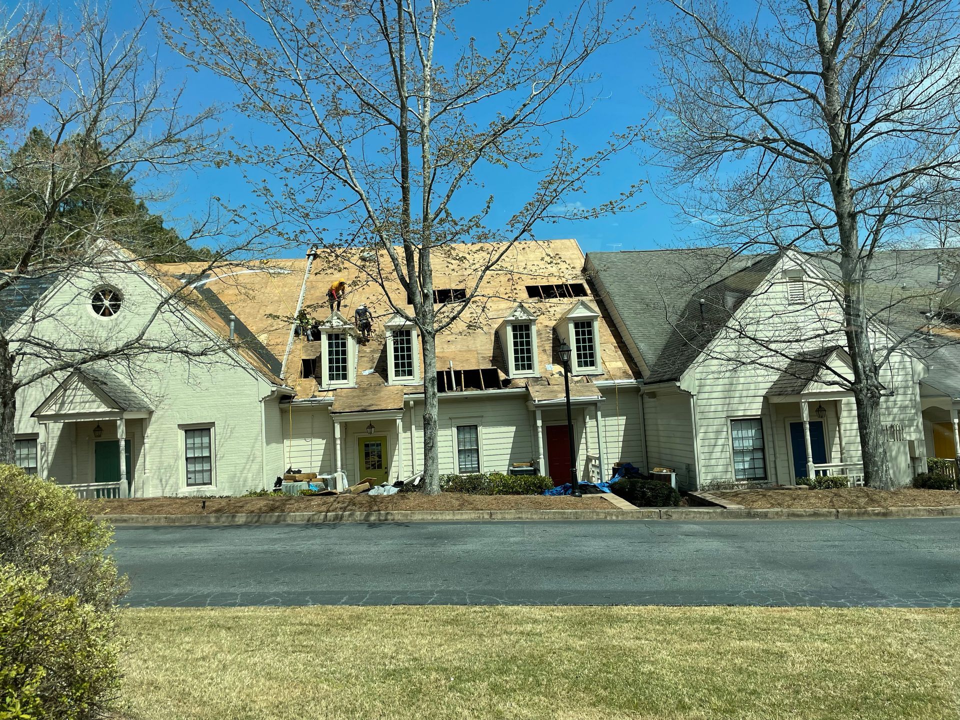 Townhouses with roofs partially removed for repairs, under a blue sky.