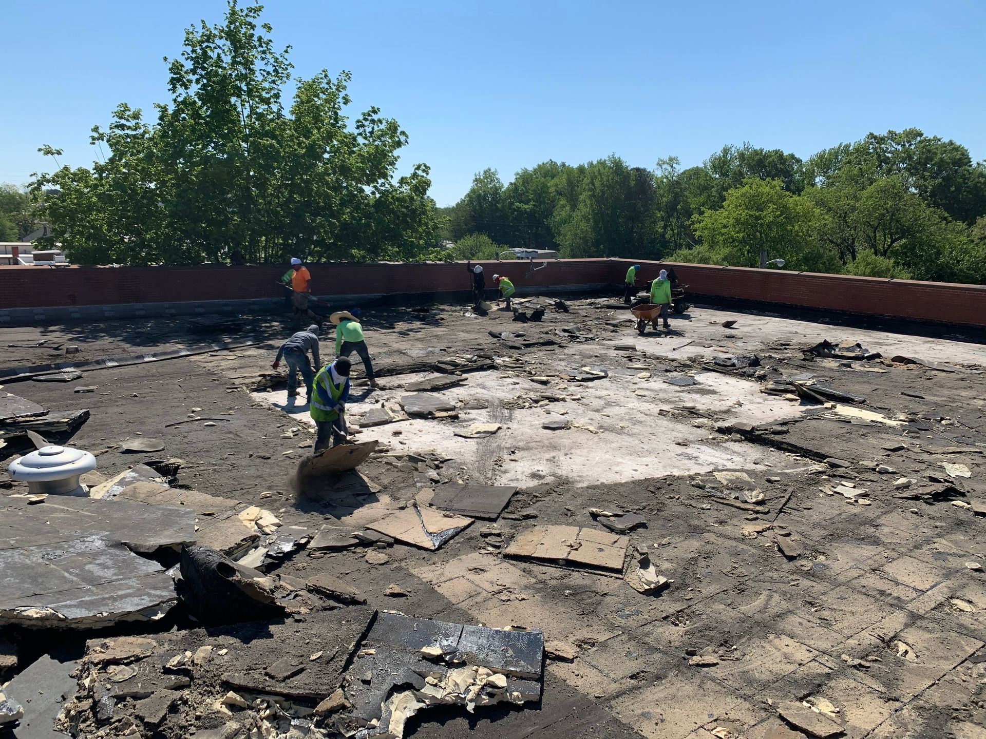 Construction workers removing a flat roof on a sunny day.