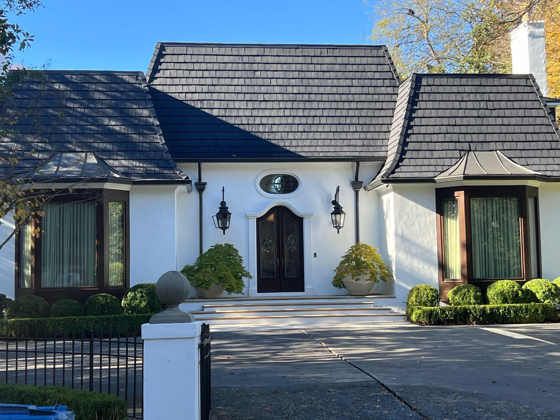 White house with black roof, black framed windows, and a circular emblem above the front door.