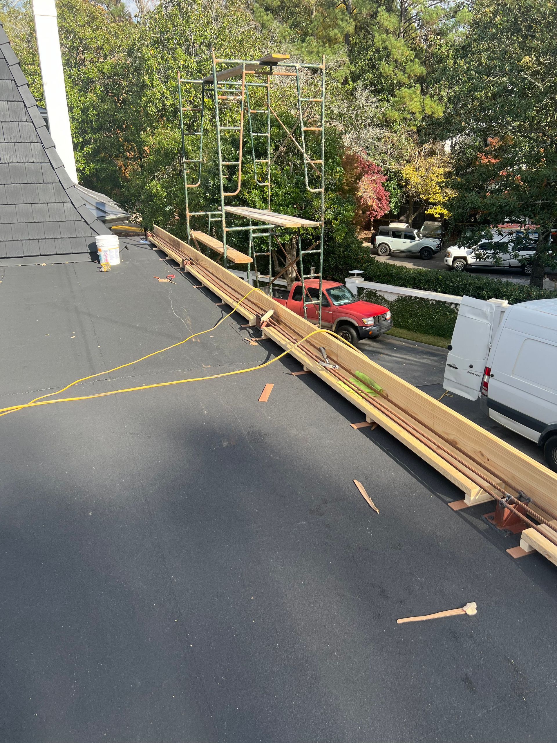Construction on a roof. Scaffolding, wooden guardrails, and a red truck are visible.