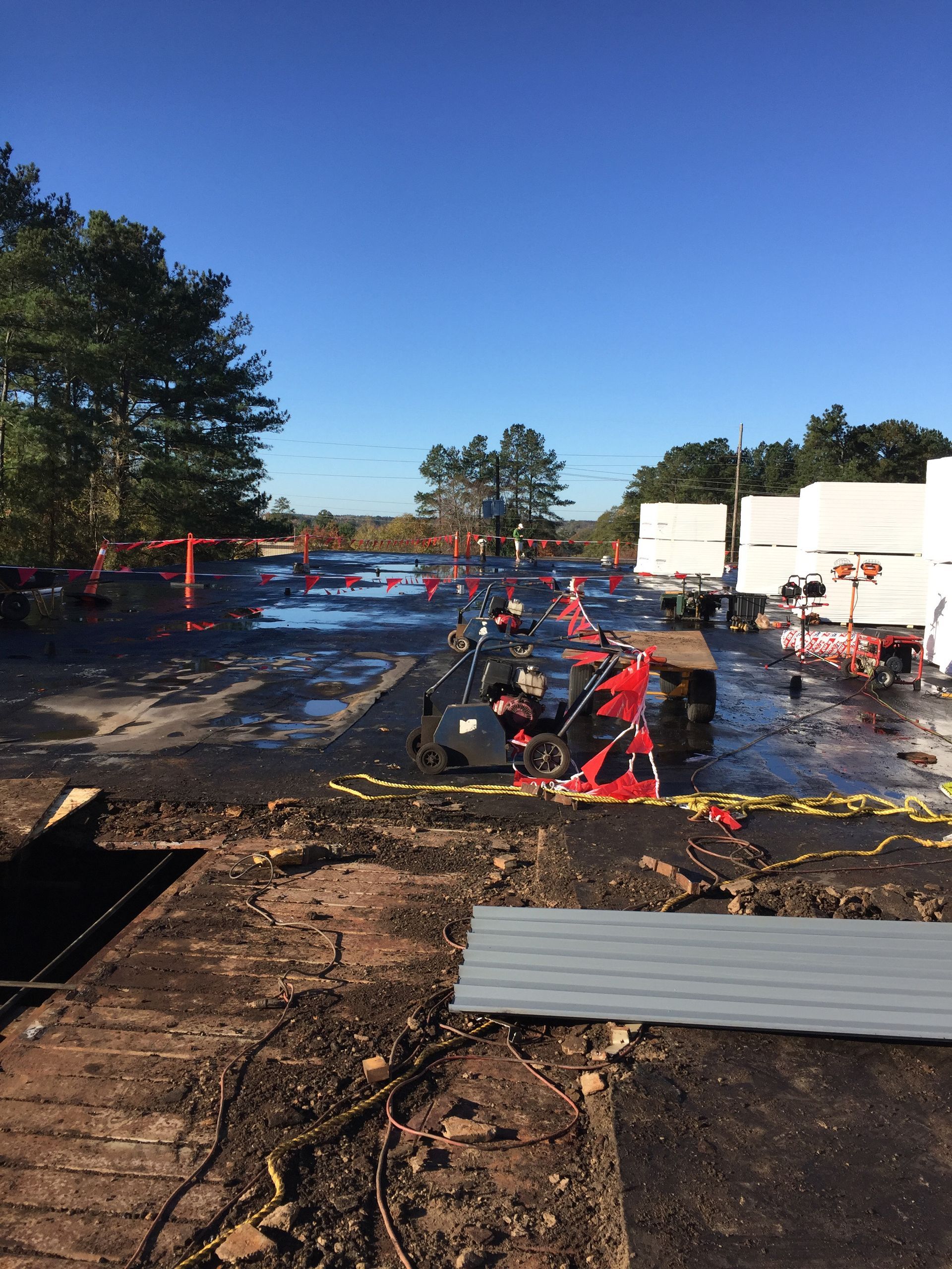 A parking lot with possible fire damage. Debris, cones, and caution tape are present. Sky is clear.