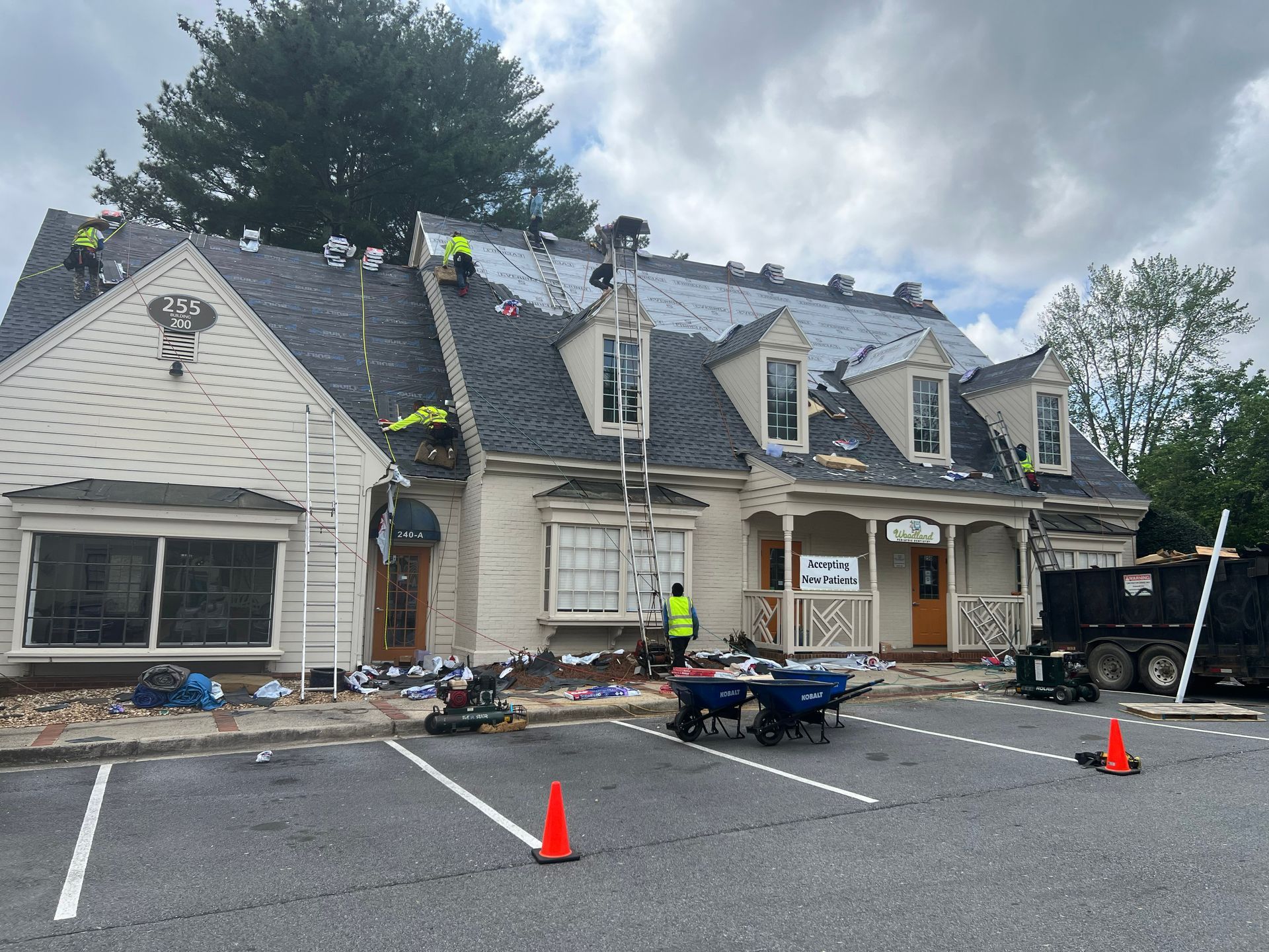 Roofers working on a building with a gray roof and beige walls.
