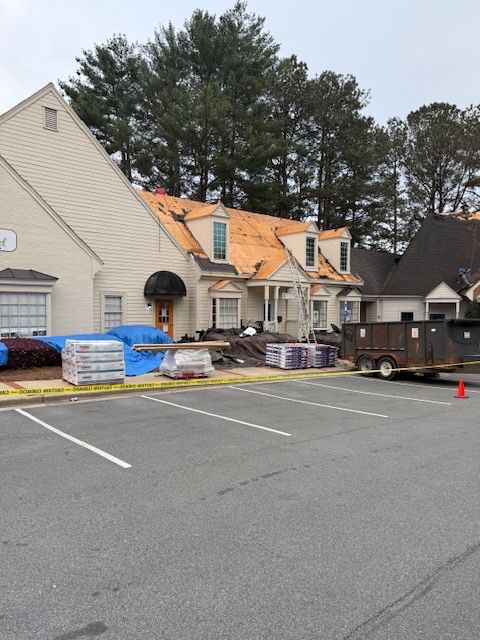 Building with roof being replaced; supplies and a dumpster are present.