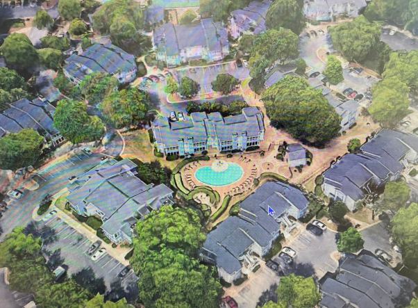 Aerial view of apartment complex with pool and surrounding trees. Buildings have dark roofs.