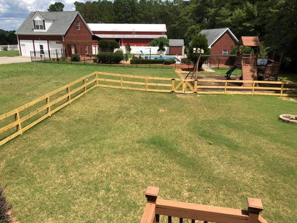 Rural farmyard with fenced grassy pasture, red barns, and a farmhouse under a cloudy sky