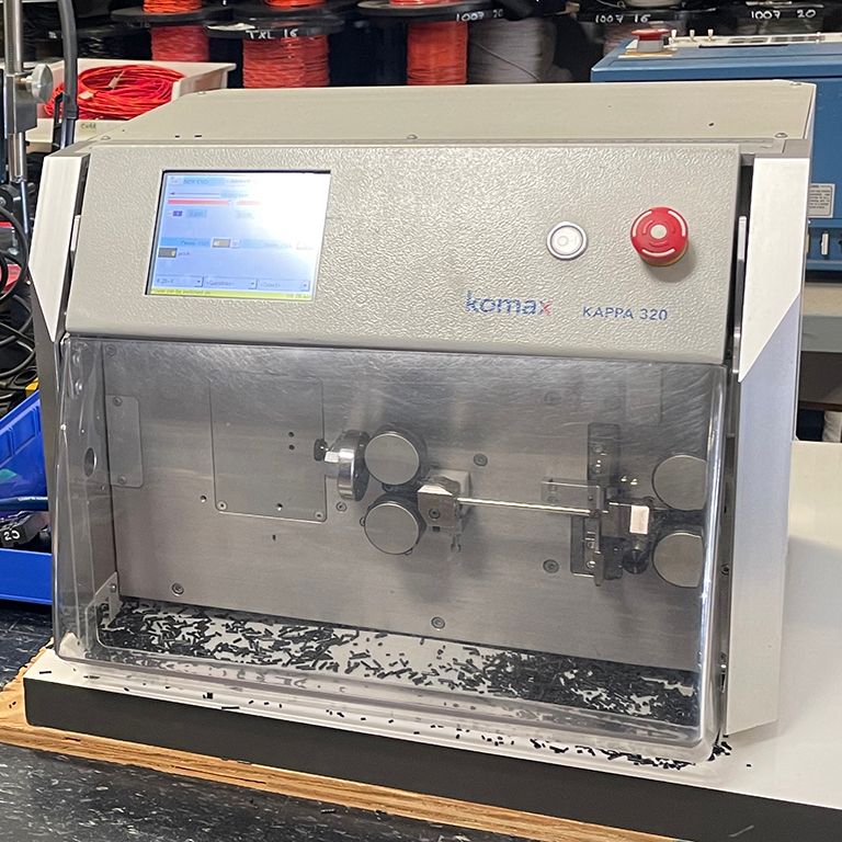 A komax wire stripping machine is sitting on a table