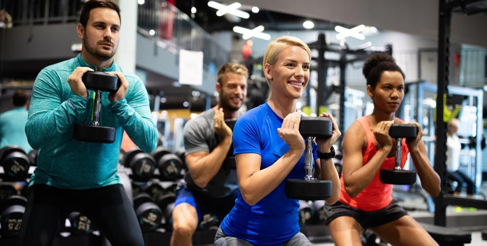 A group of people are lifting dumbbells in a gym.