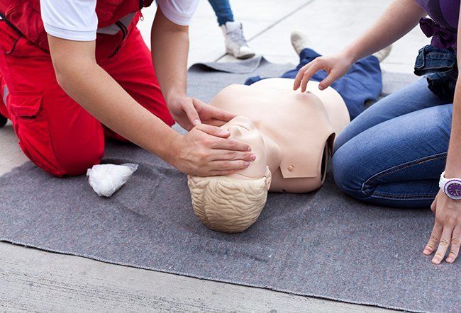 A man and a woman are kneeling down next to a mannequin.