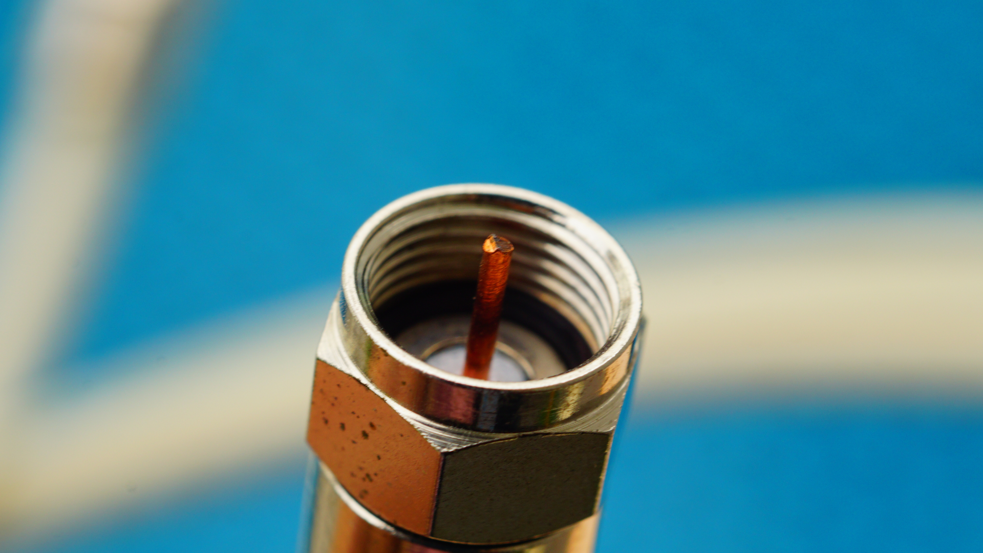 A close up of a coaxial cable connector on a blue background.