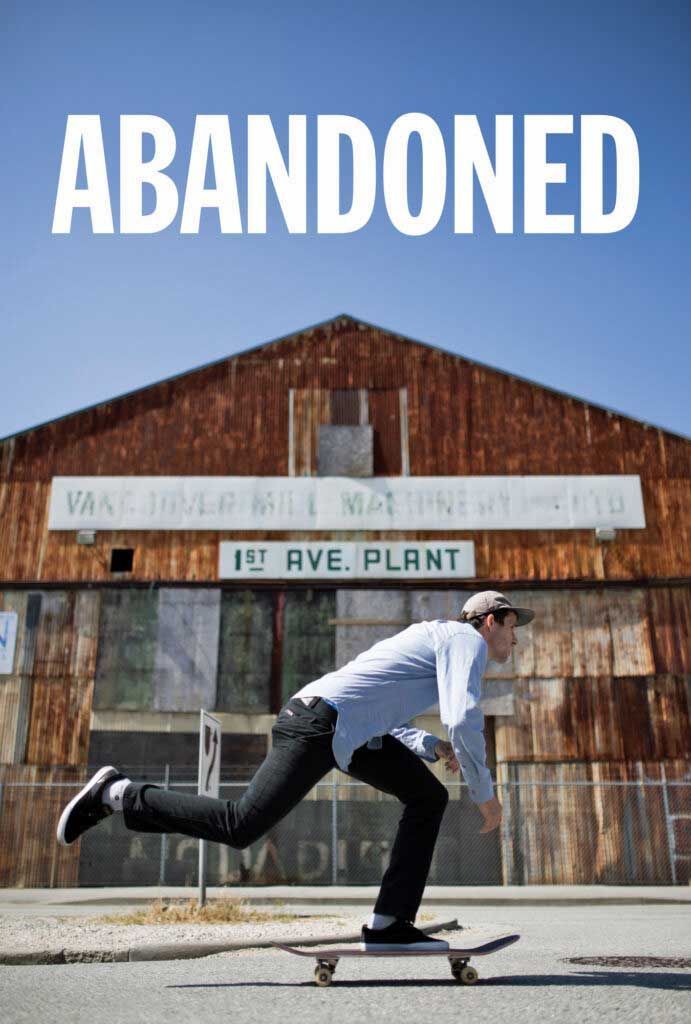 A man is riding a skateboard in front of an abandoned building