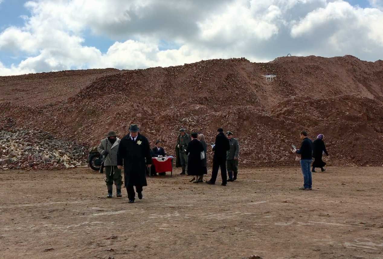 A group of people standing in front of a large pile of dirt