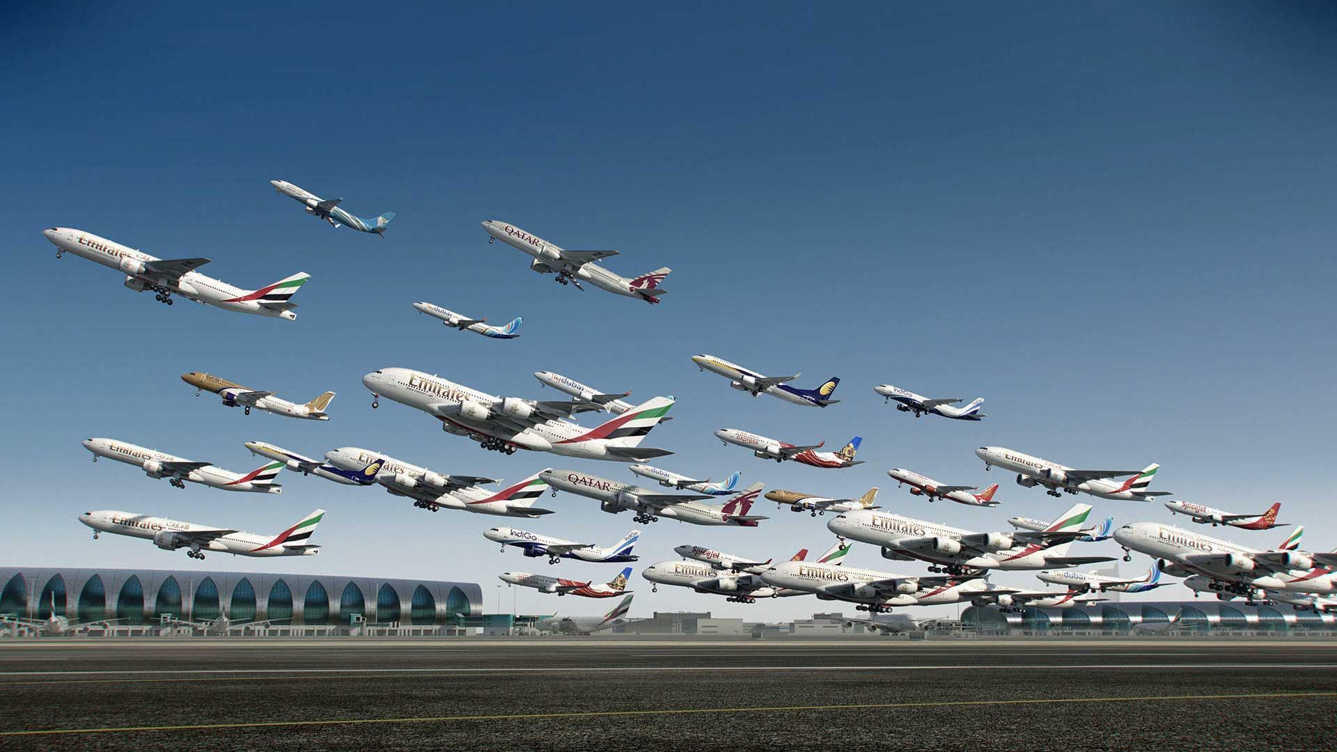 A bunch of planes are flying over an airport runway