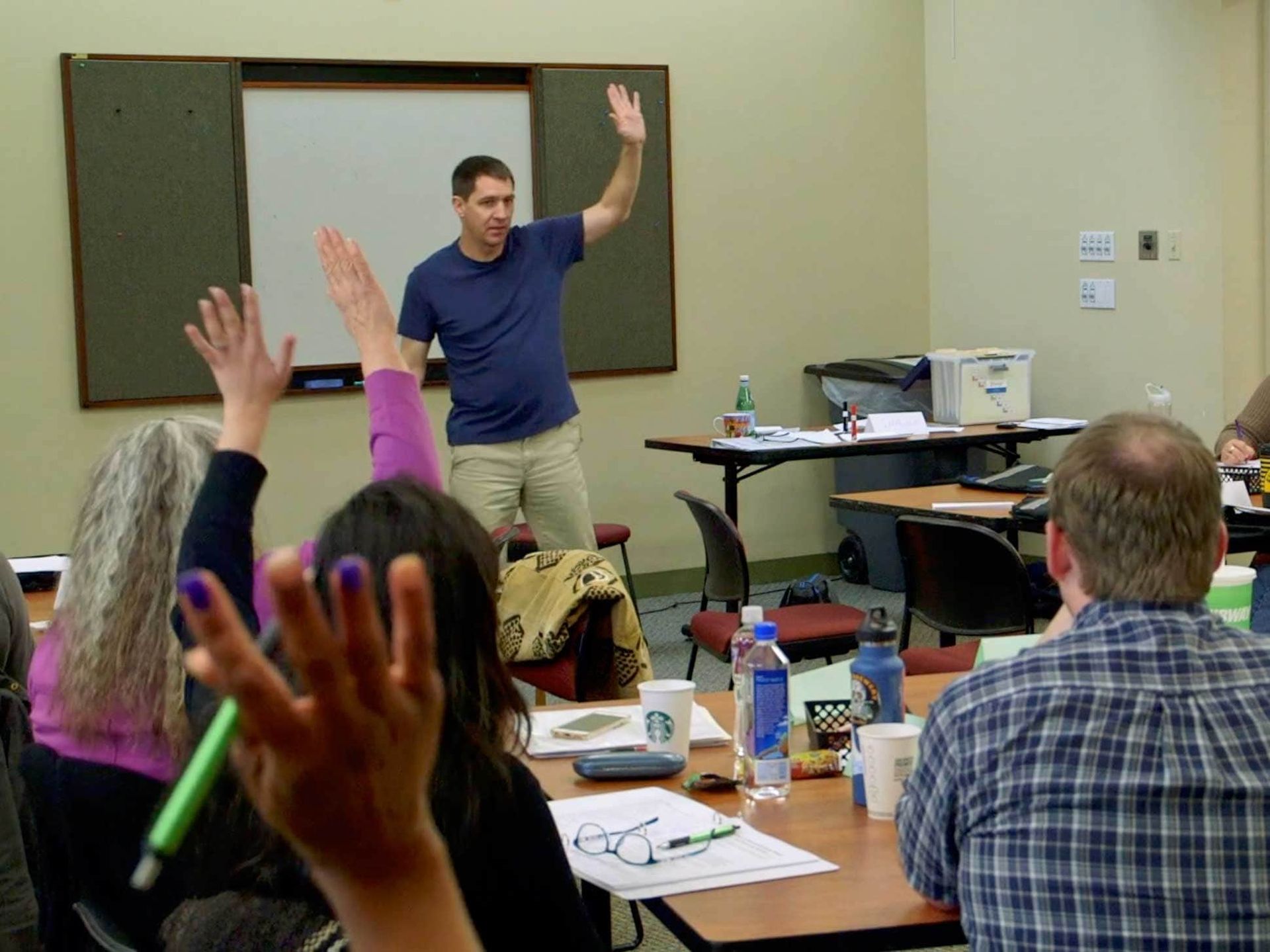 A group of people are raising their hands in a classroom