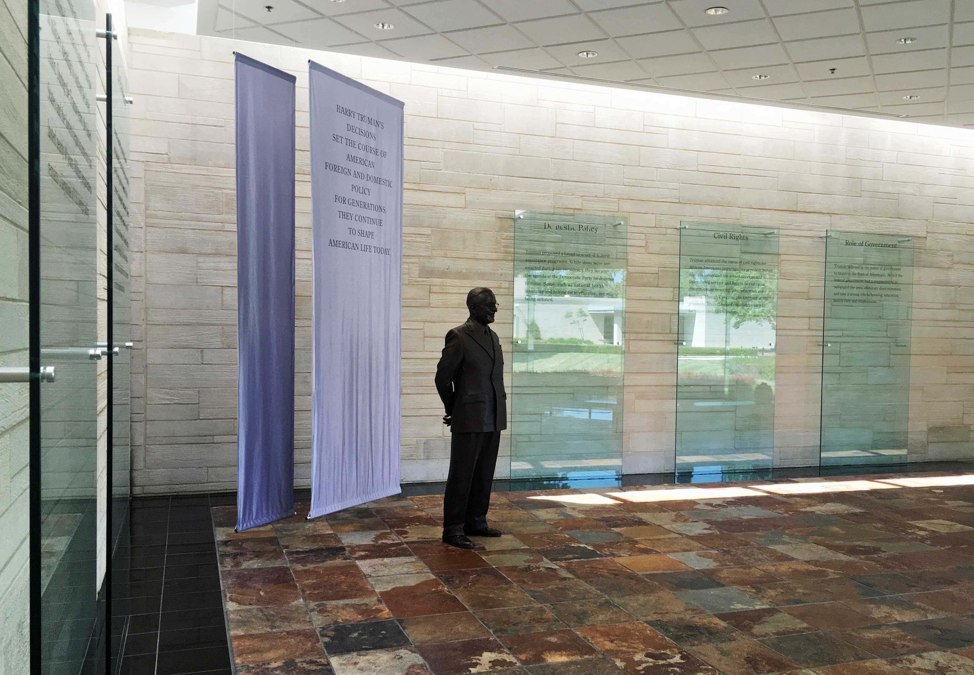 A statue of a man is standing in a room with a few flags