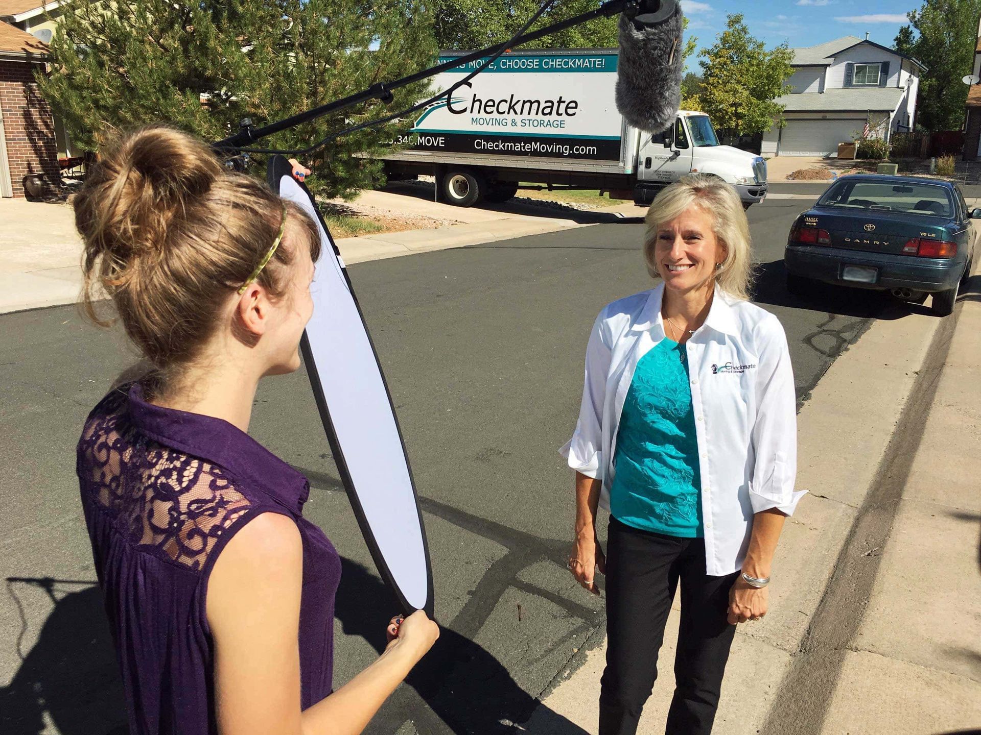 A woman is talking to another woman in front of a chestmate truck