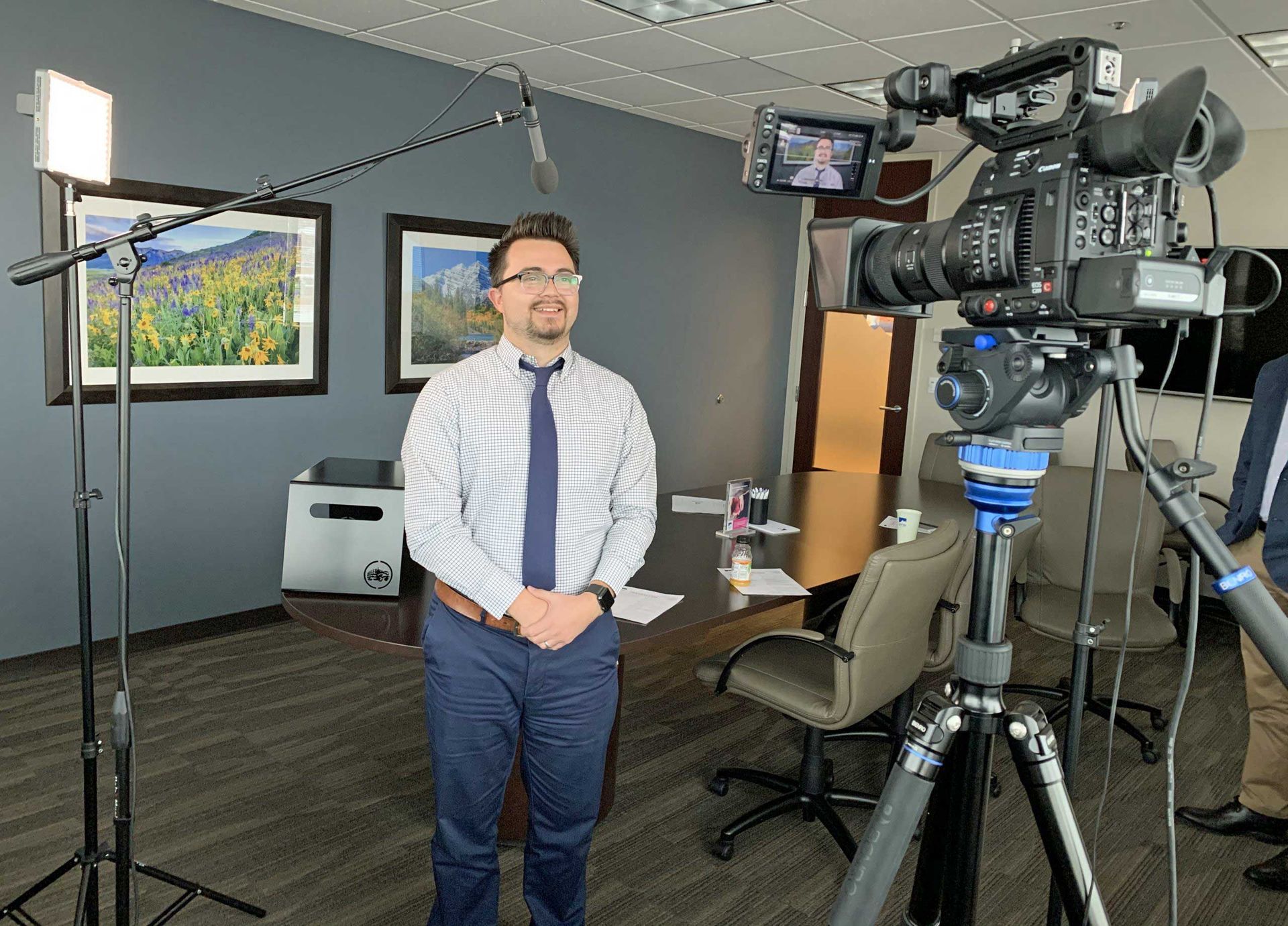 A man is standing in front of a camera in a conference room.