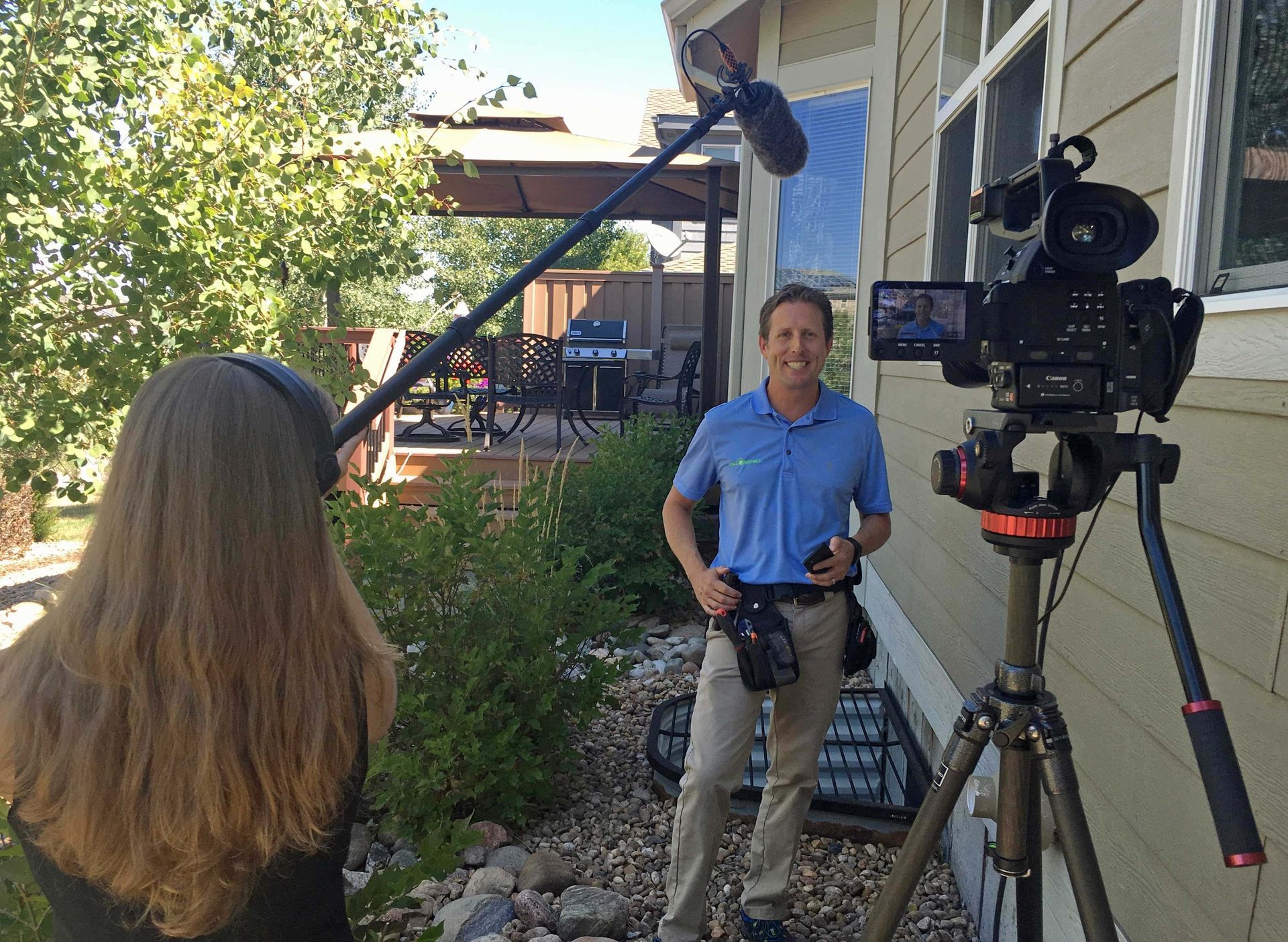 A man is standing in front of a camera while a woman looks on.