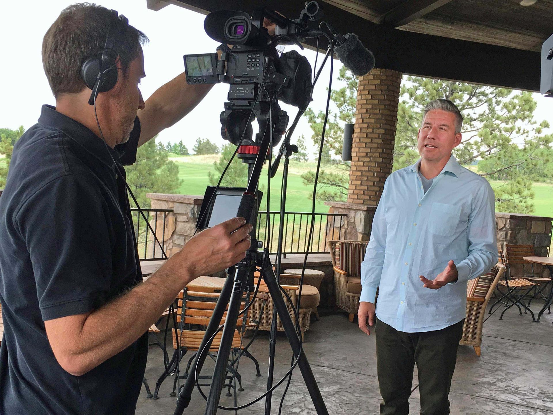 A man in a blue shirt is being interviewed by a cameraman