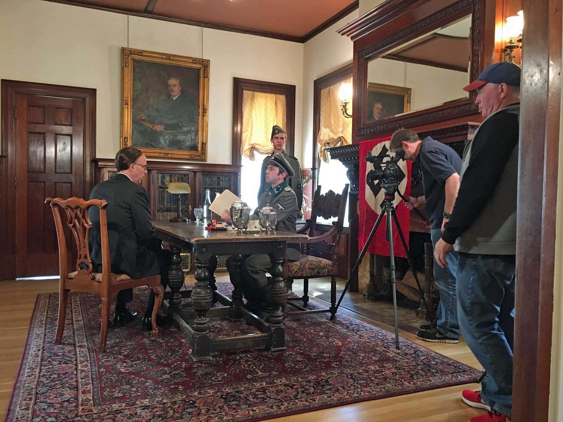 A group of men are sitting around a table in a living room.