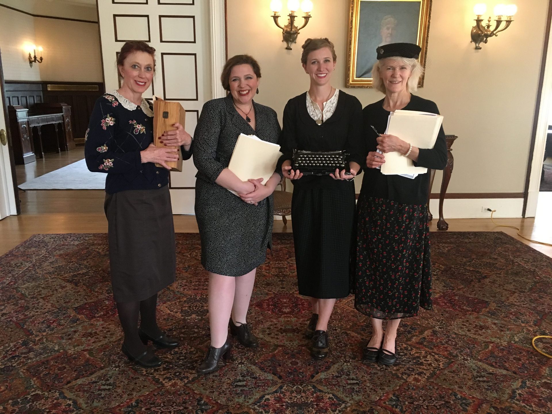 A group of women standing in a room holding papers