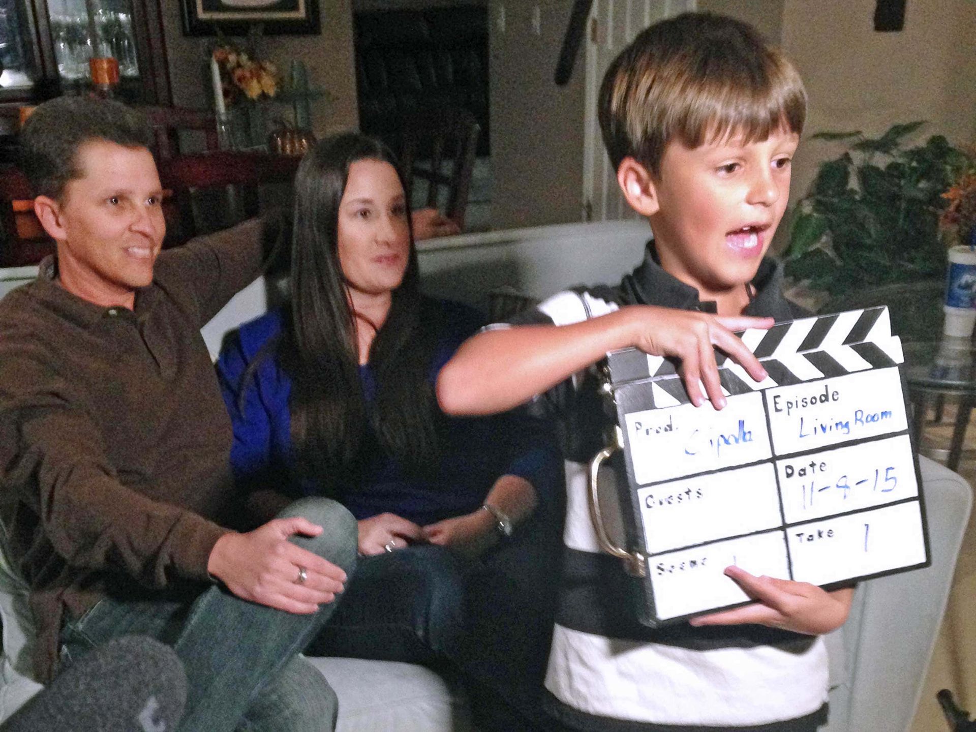 A young boy is holding a clapper board that says comedy