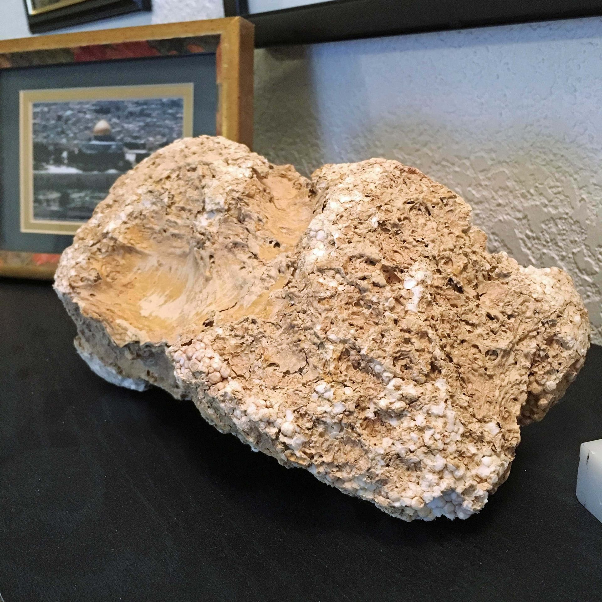A large rock is sitting on a table next to a framed picture
