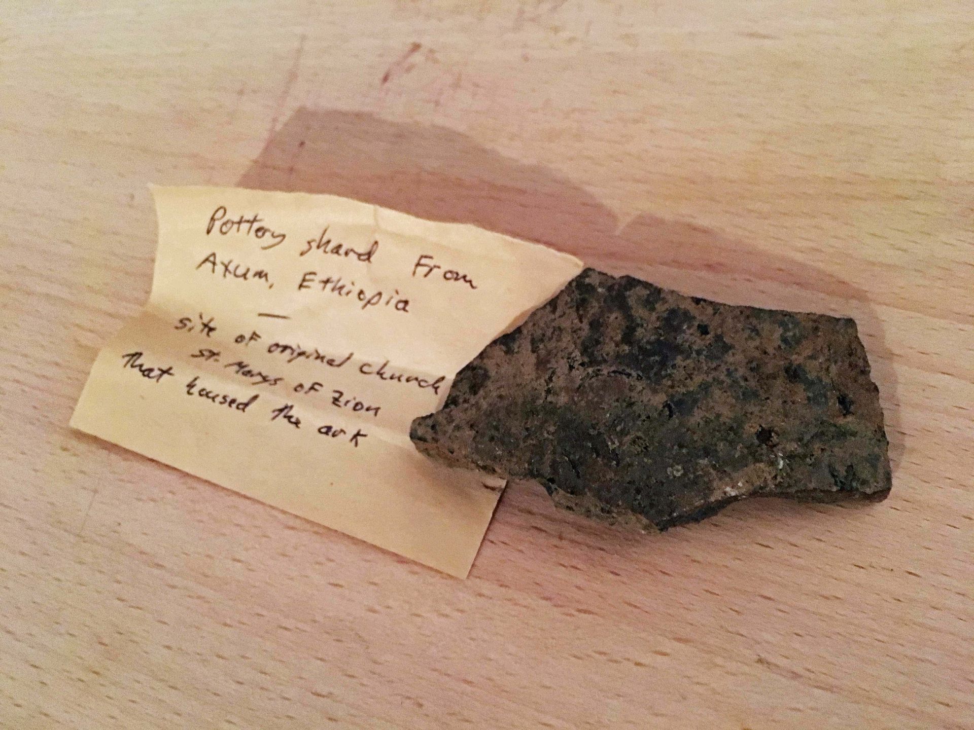 A piece of rock with a piece of paper on it that says pottery shard from asia ethiopia