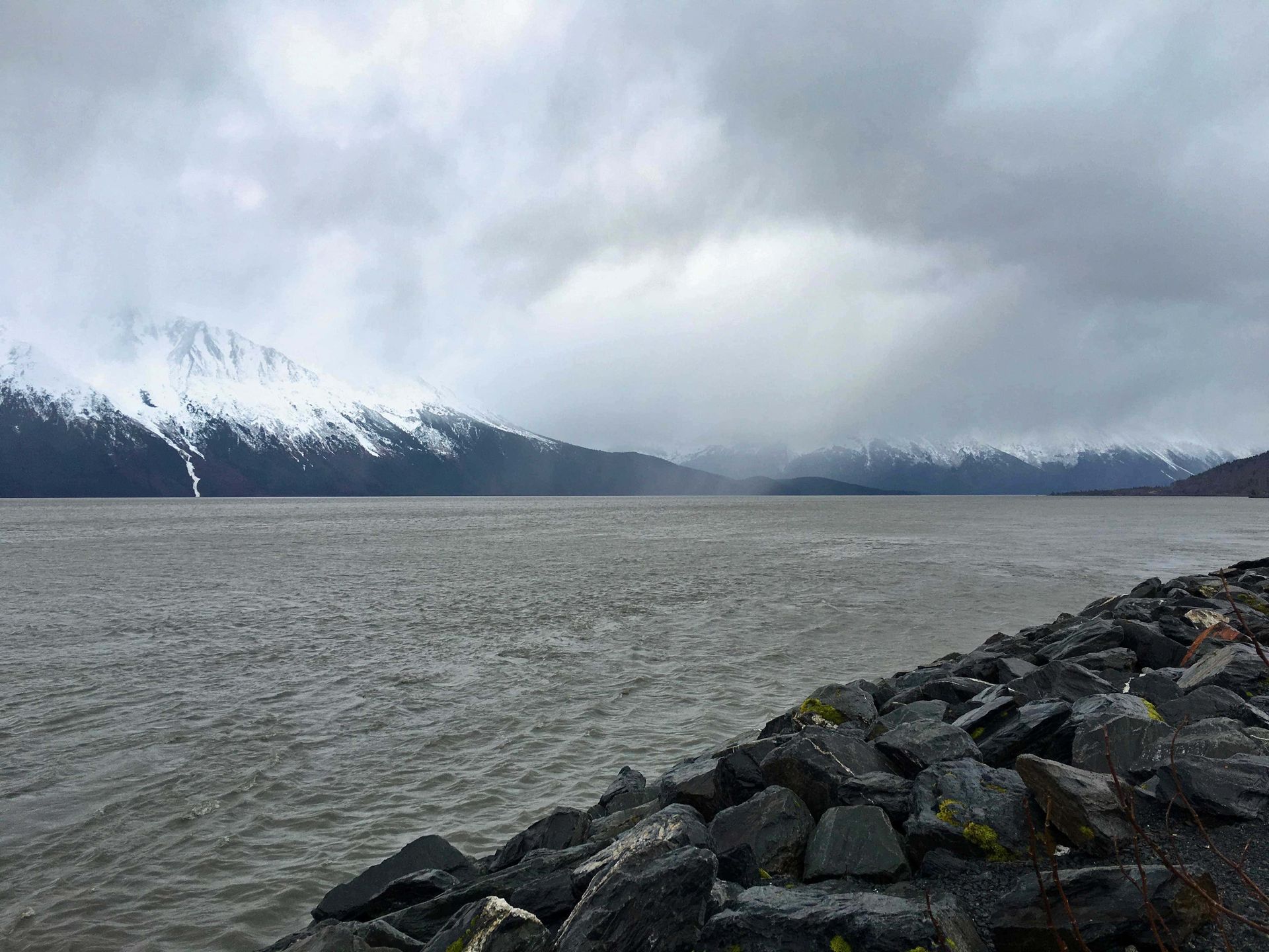 A large body of water with mountains in the background and a rocky shoreline.