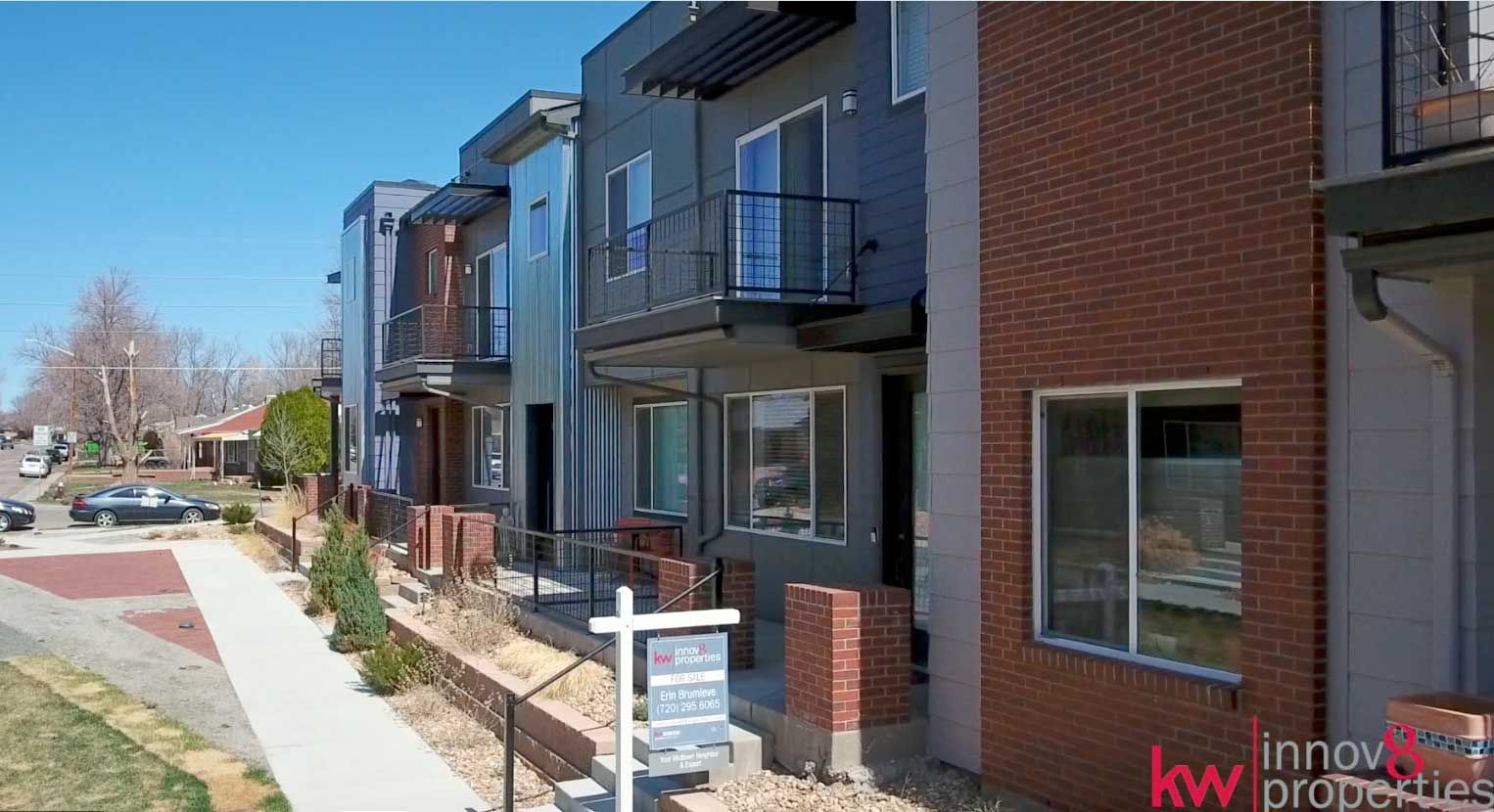 A row of houses with a for sale sign in front of them.