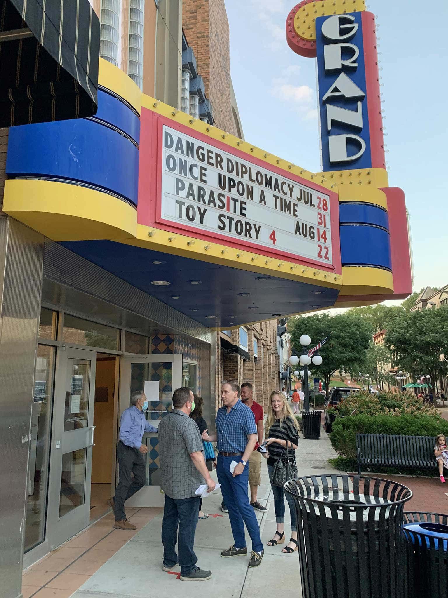 A group of people are standing outside of a movie theater.