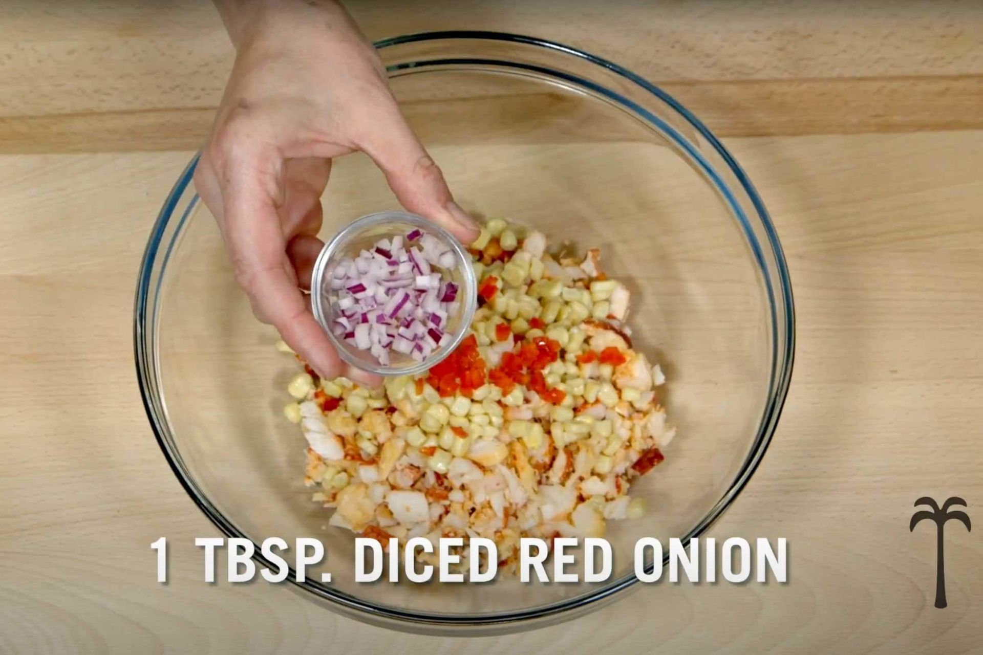A person is adding diced red onion to a bowl of food.