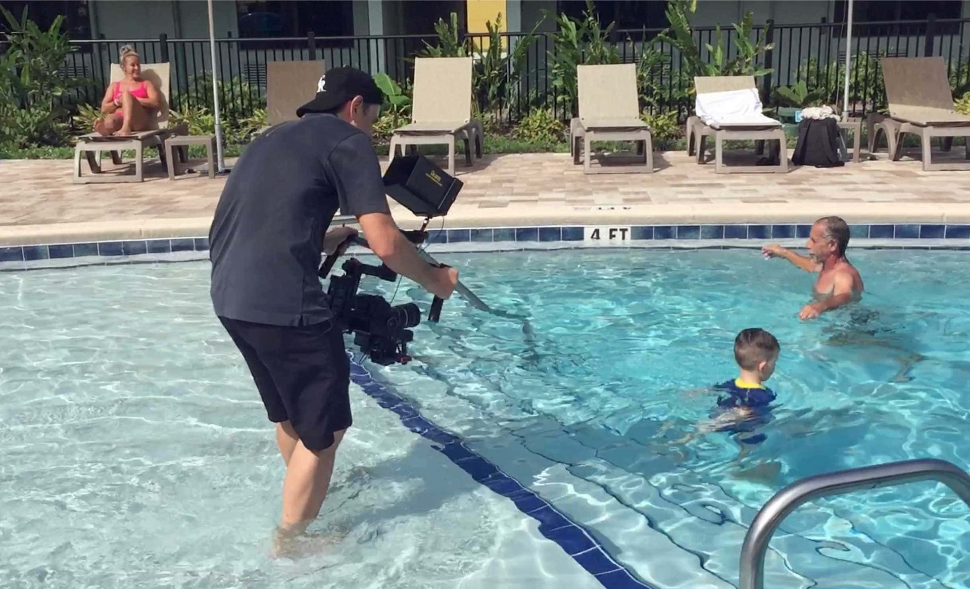 A man is taking a picture of people in a pool that is 4 feet deep