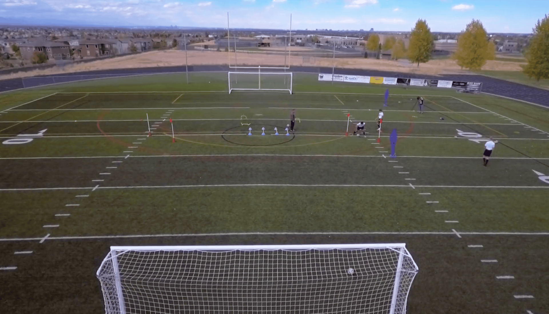An aerial view of a soccer field with a goal in the foreground
